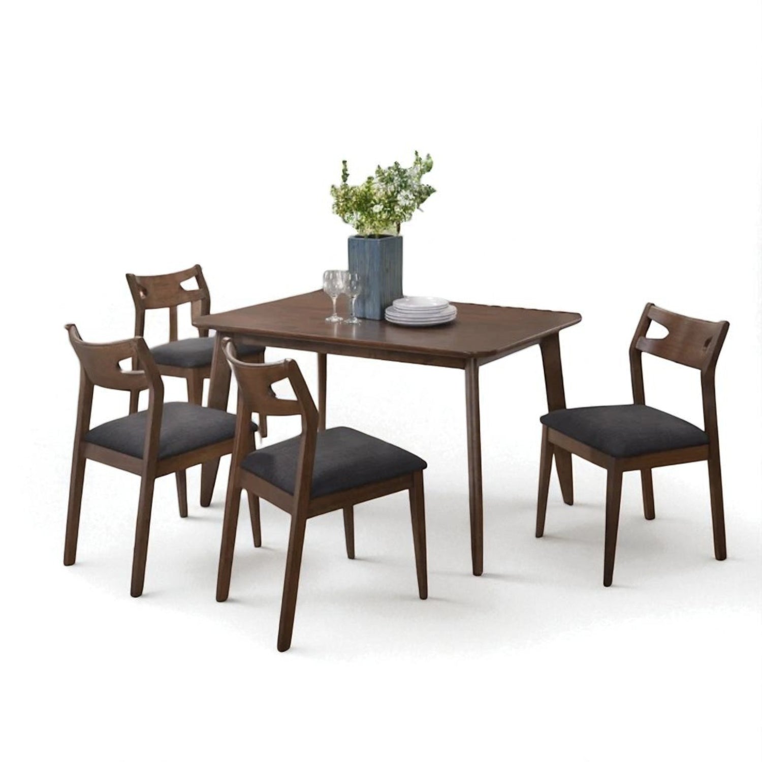Contemporary wooden dining set with a rectangular table and four cushioned chairs. Features tapered legs, rounded edges, and dark fabric seats. Styled with a blue vase, greenery, glassware, and white plates on a plain white background.