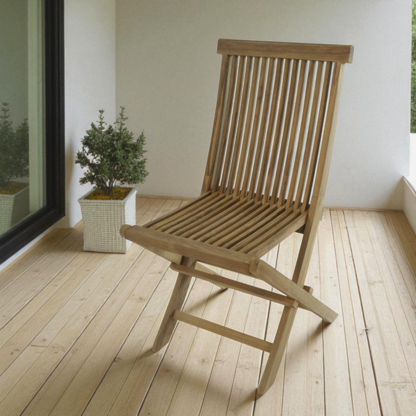 Java outdoor folding chair made of teak wood, placed on a wooden deck beside a white pot with green foliage and a large glass window