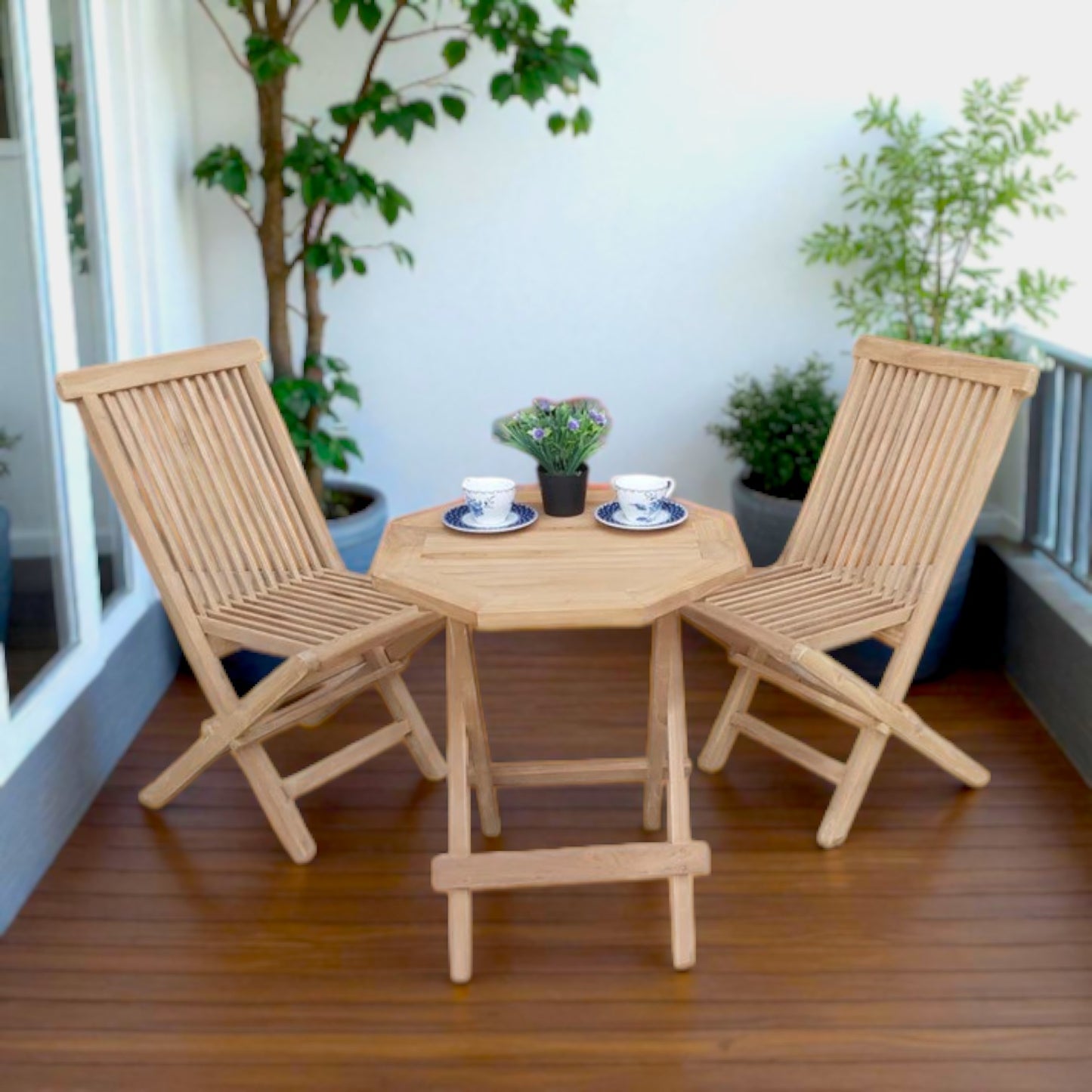 Teak outdoor balcony set featuring two Java Folding Chairs and a Cilacap Side Table with hexagonal top, styled with patterned teacups and potted flowers for a cozy patio vibe.