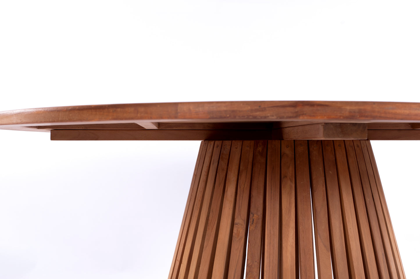 Nusa Dua round wooden outdoor dining table with slatted base, styled with white tableware and floral centerpiece on a garden patio deck.