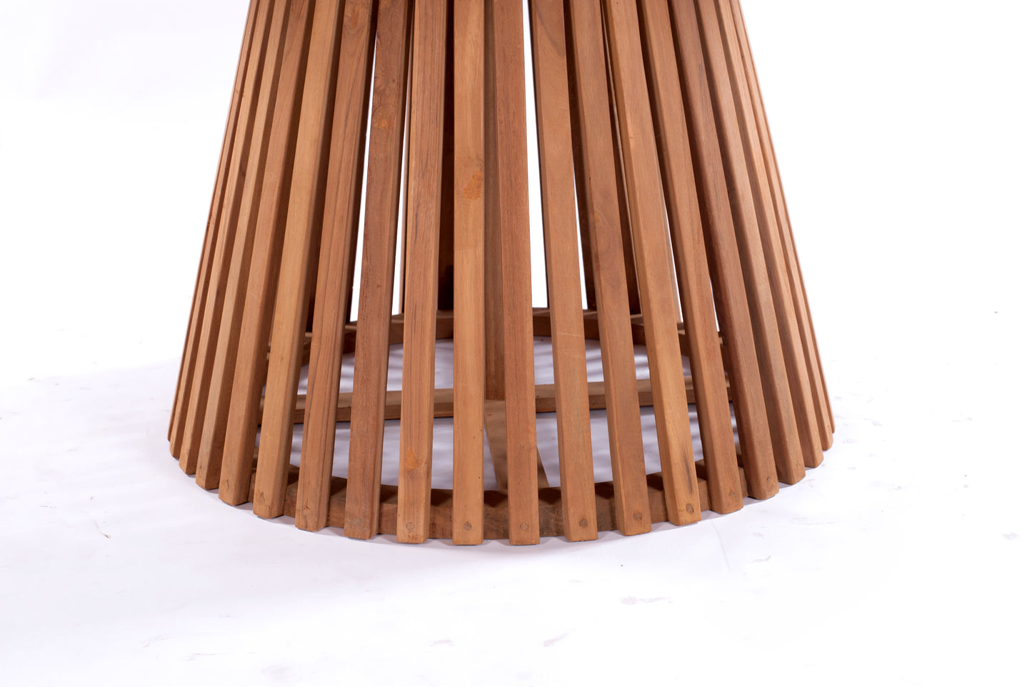 Nusa Dua round wooden outdoor dining table with slatted base, styled with white tableware and floral centerpiece on a garden patio deck.