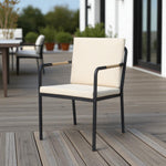 Hollviken outdoor dining chair with black metal frame, beige cushions, and wooden armrests on a modern patio deck.