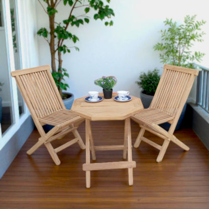 Teak outdoor balcony set featuring two Java Folding Chairs and a Cilacap Side Table with hexagonal top, styled with patterned teacups and potted flowers for a cozy patio vibe.