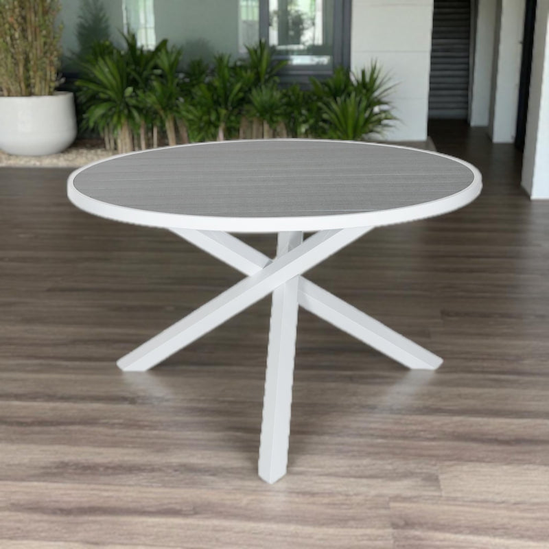 Pisa Outdoor Dining Table with round grey top and white aluminum X-shaped base, styled for modern patio or garden settings.