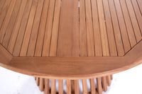 Nusa Dua round wooden outdoor dining table with slatted base, styled with white tableware and floral centerpiece on a garden patio deck.