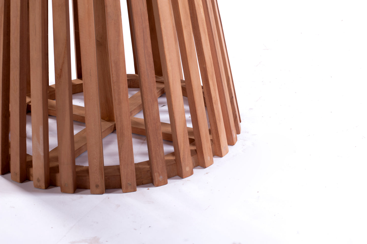 Nusa Dua round wooden outdoor dining table with slatted base, styled with white tableware and floral centerpiece on a garden patio deck.